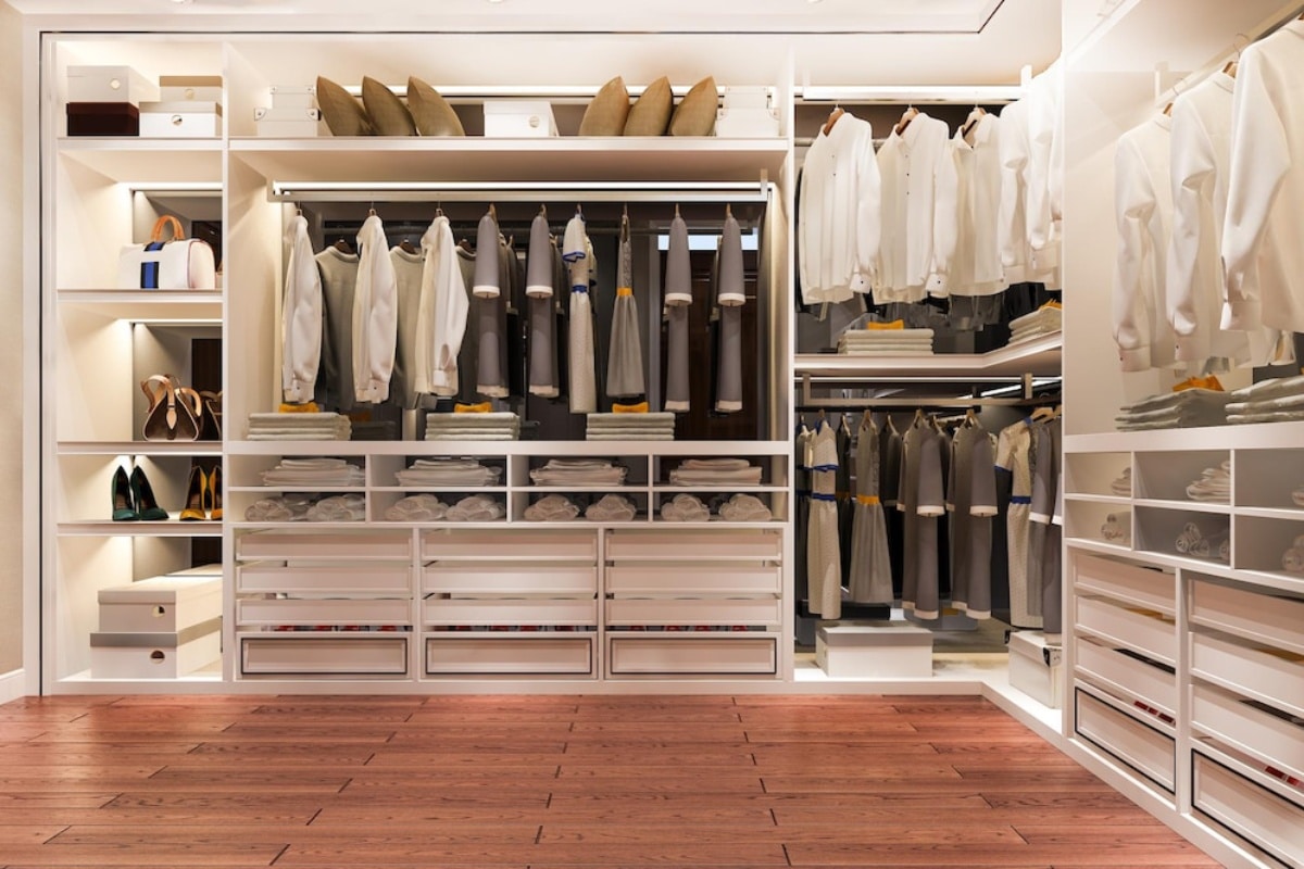 A well-organized, luxurious walk-in closet with neatly arranged clothes, shoes, and accessories on multiple shelves.