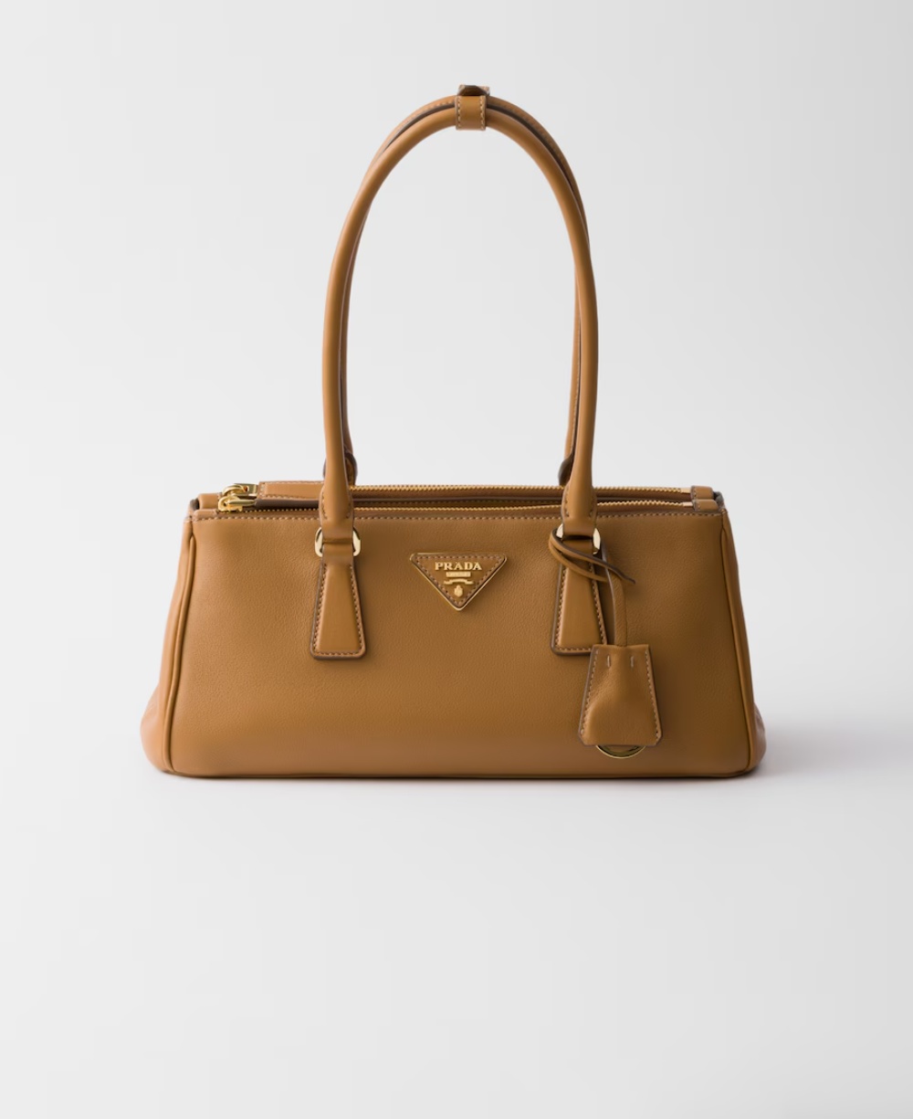  Elegant tan leather handbag with designer logo, double handles, and gold-tone hardware on a white background.