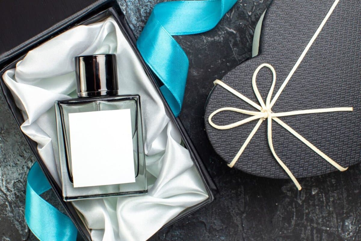 A bottle of perfume in a gift box with a blue ribbon and a heart-shaped gift box tied with a string.